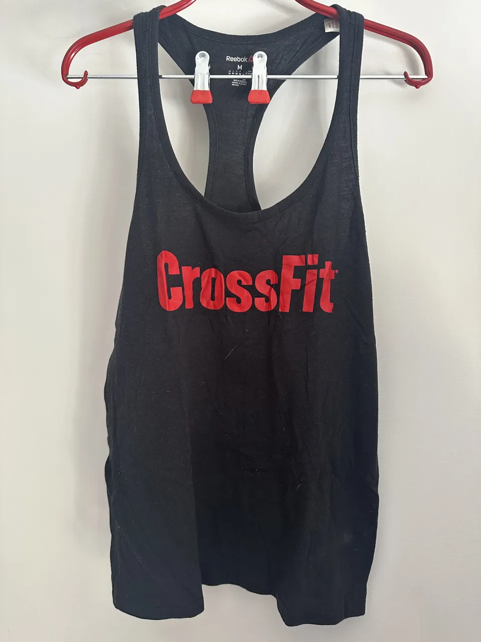 Musculosa deportiva negra de Reebok con estampa "CrossFit" en rojo. Ideal para entrenamientos o uso casual.