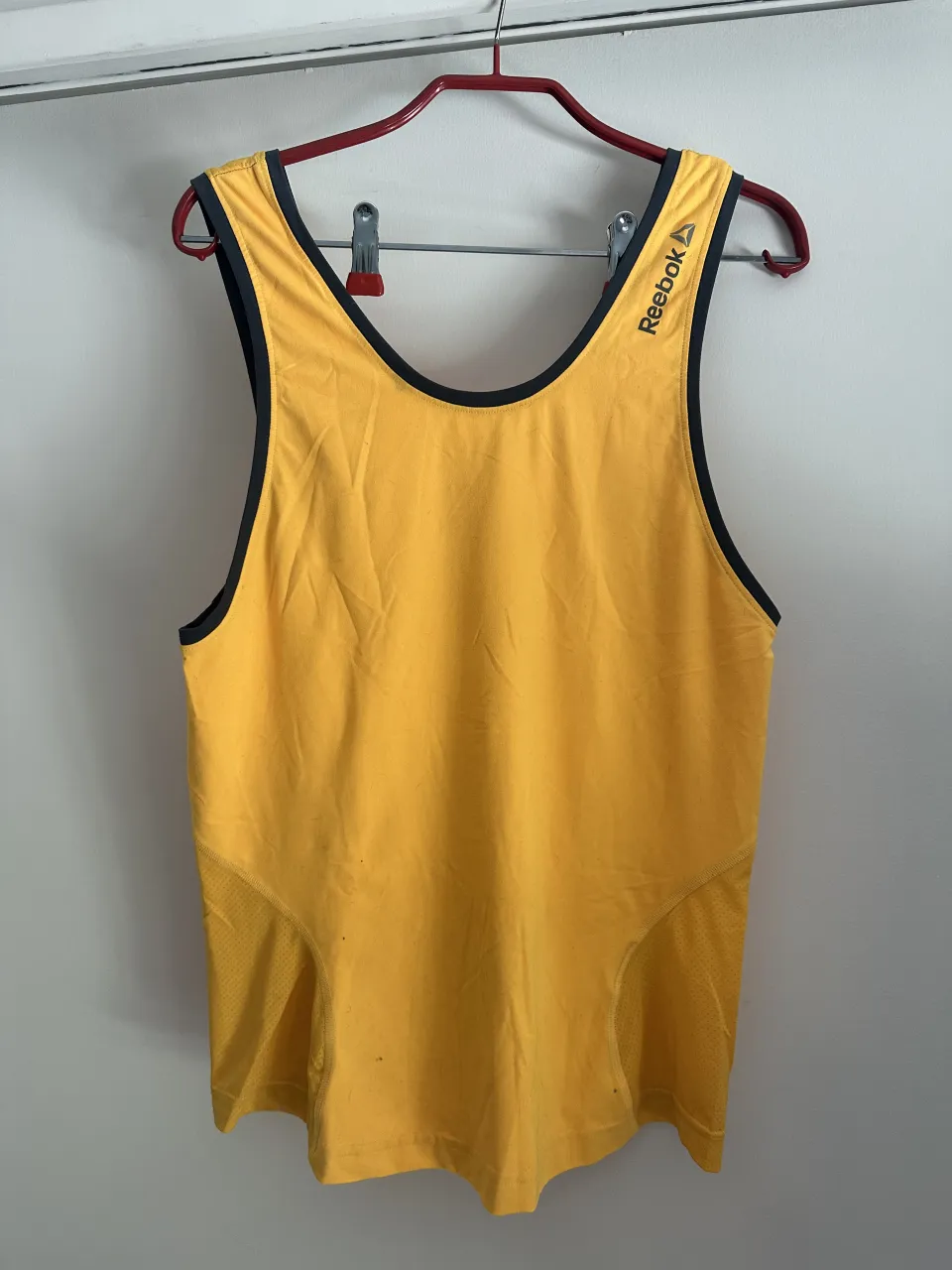 Musculosa deportiva amarilla con detalles en negro. Ideal para entrenar o para un look casual y cómodo.