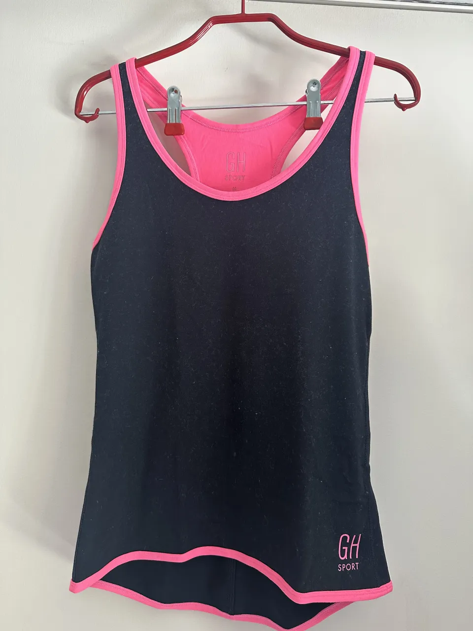 Musculosa deportiva negra con detalles en rosa. Ideal para entrenar o para un look casual y cómodo. Marca GH SPORT.