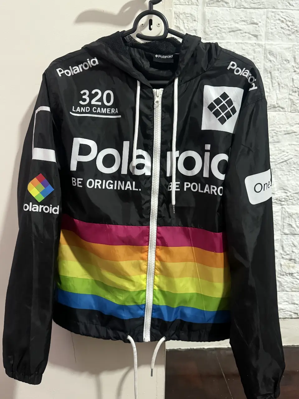 Campera rompevientos de la marca Polaroid, con diseño retro y detalles de arcoíris en la parte inferior. Ideal para un look casual y urbano. Nueva sin uso.