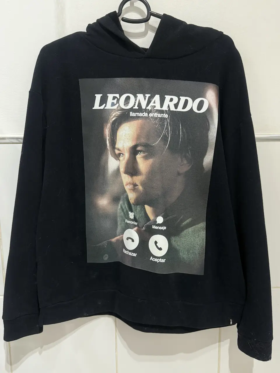 Buzo canguro negro con estampado frontal de Leonardo DiCaprio y texto "LEONARDO" con diseño de llamada entrante. Espalda estampada. 47 STREET