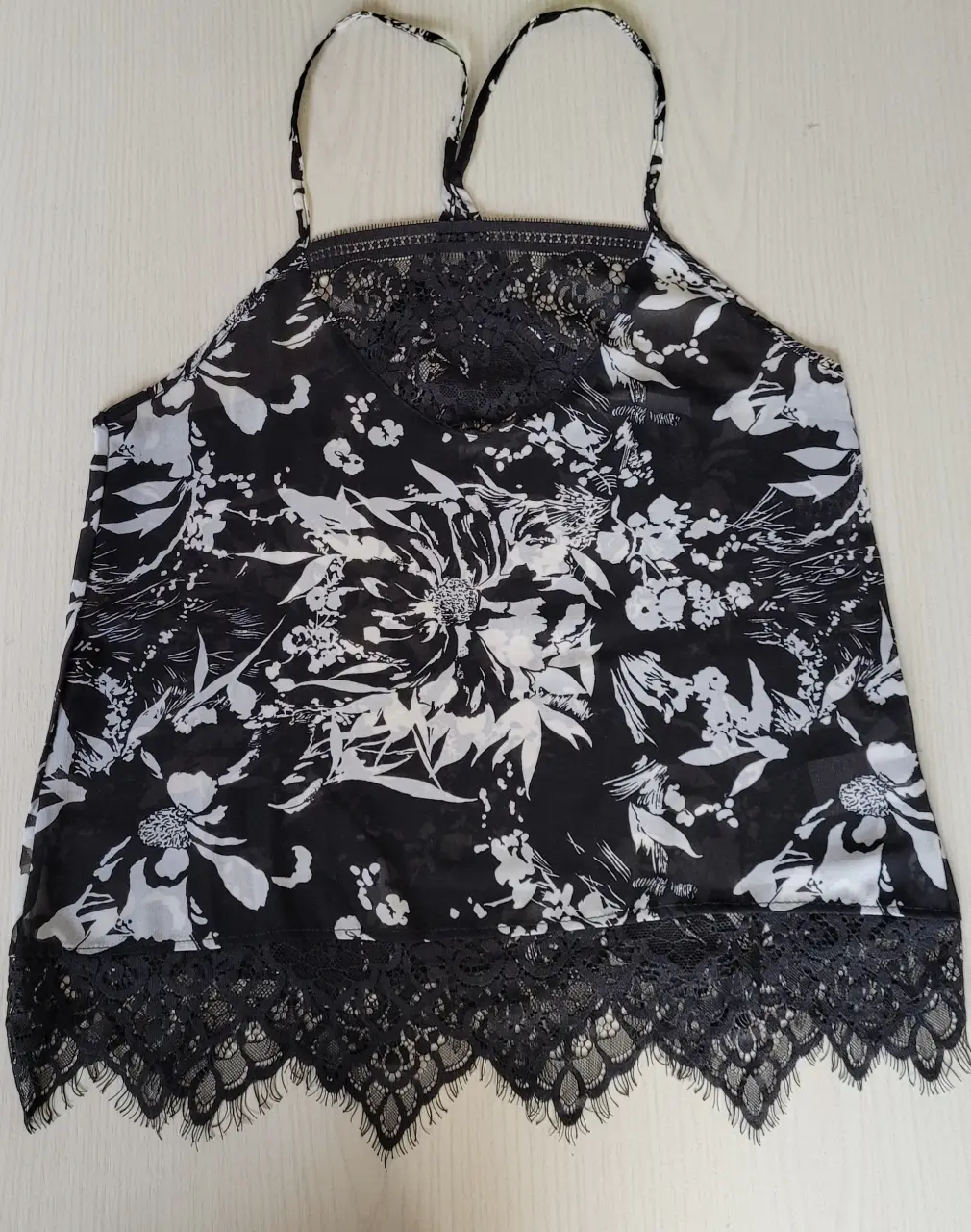Blusa con tirantes y detalles de encaje en el escote y el borde inferior en perfecto estado. Ideal para un look fresco y femenino.