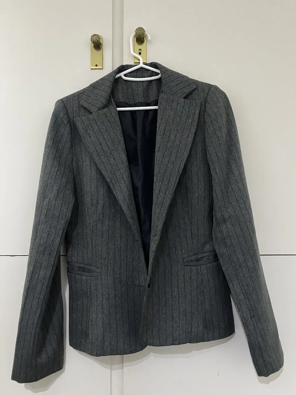 Blazer gris a rayas para mujer, ideal para un look formal o de trabajo. Corte clásico y elegante.