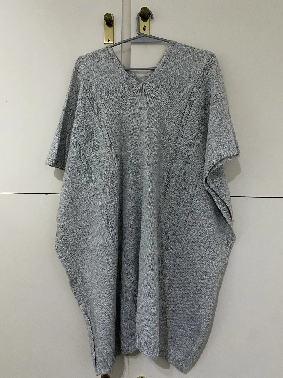 Poncho de lana gris, tejido con diseño en relieve. Ideal para un look casual y abrigado.