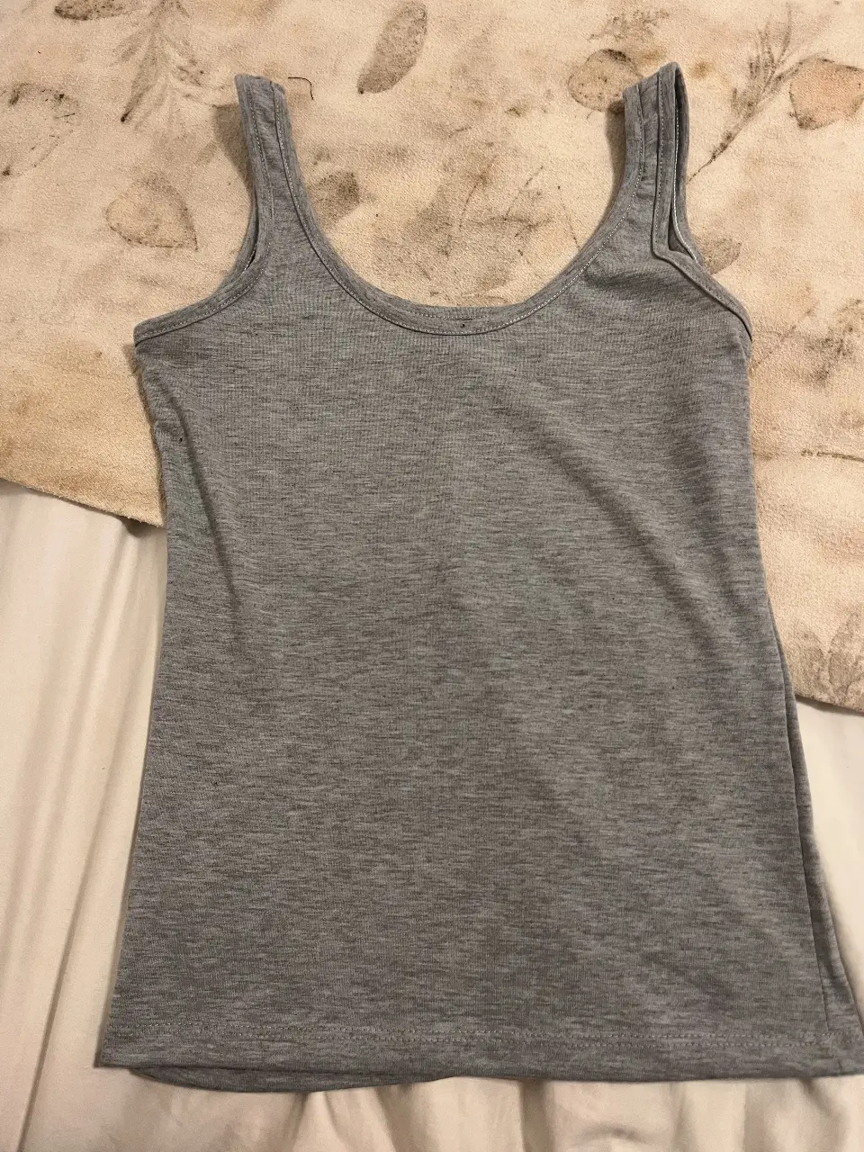 Musculosa gris de mujer, ideal para el verano. Confeccionada en tela suave y cómoda, perfecta para un look casual.