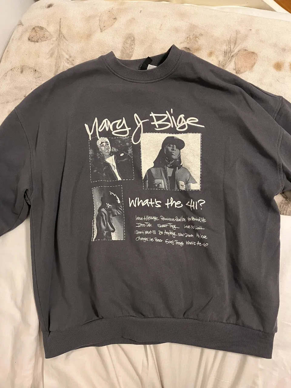 Buzo de cuello redondo gris oscuro con estampado de Mary J. Blige y la frase "What's the 411?". Ideal para un look casual y urbano.