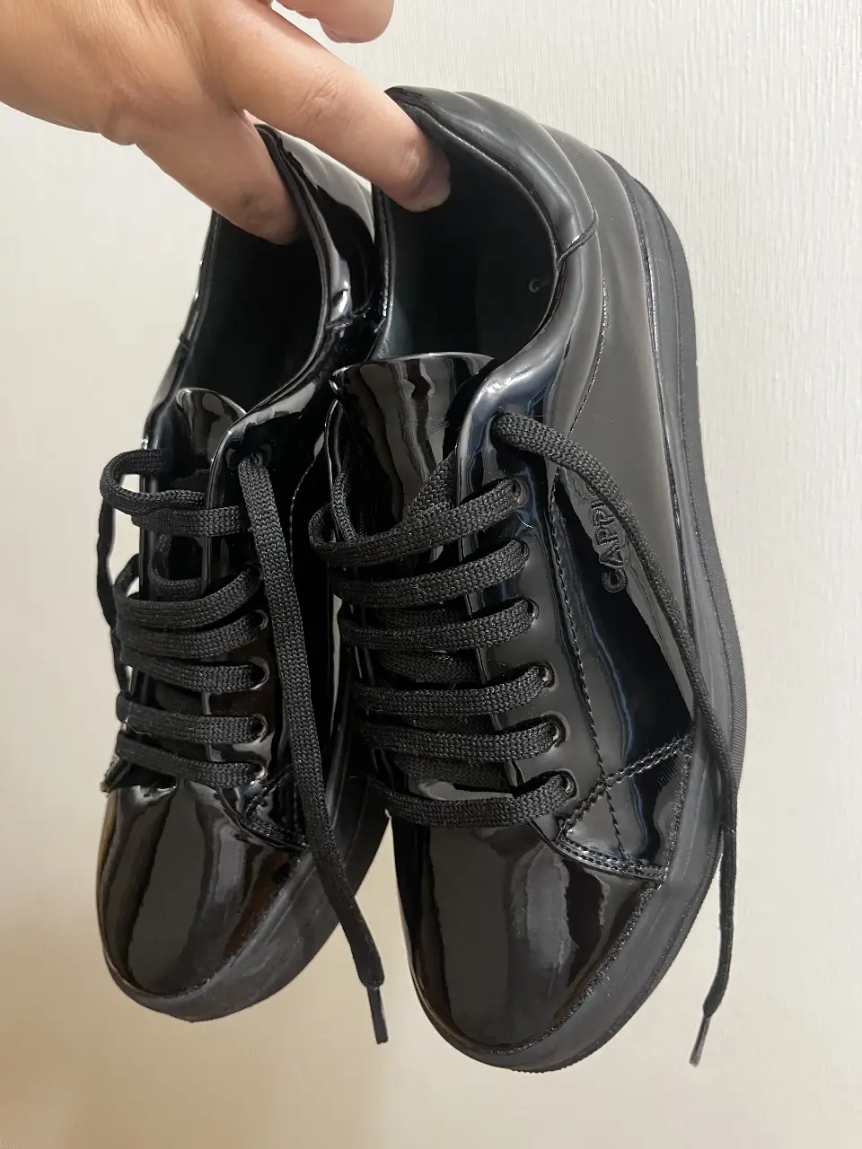 Zapatillas negras de charol para hombre. Diseño elegante y moderno, ideales para un look casual o para ocasiones especiales. Su acabado brillante le da un toque sofisticado.