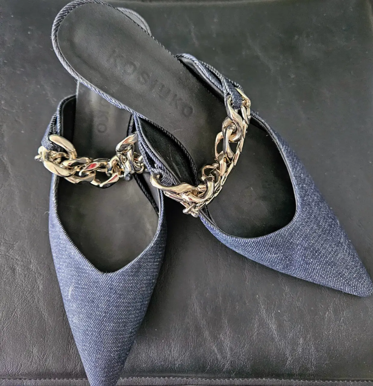 Sandalias de jean azul con detalle de cadena dorada. Diseño elegante y moderno, ideales para complementar cualquier look.