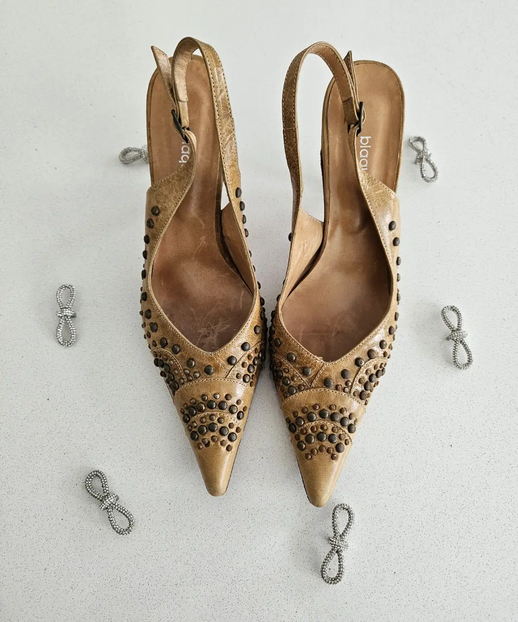 Elegantes zapatos de taco alto color marrón con detalles de tachas. Ideales para fiestas y eventos especiales.