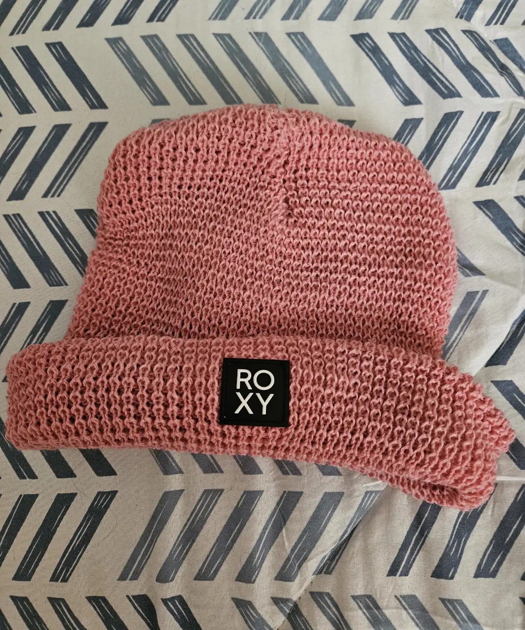 Gorro tejido de color rosa, con el logo de la marca Roxy en la parte delantera. Ideal para un look casual y abrigado.