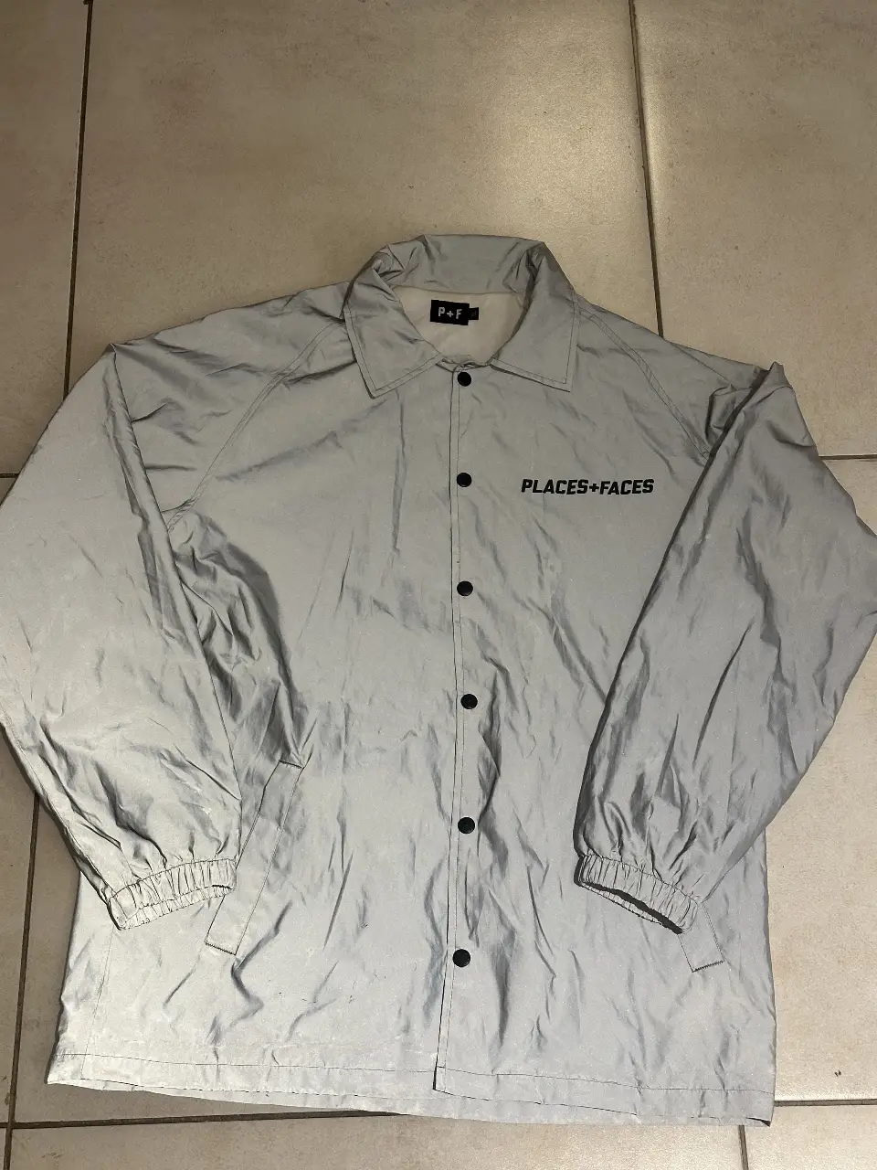 Campera rompevientos original reflectiva Places + Faces para hombre, modelo coach jacket 3M. Ideal para usar en la calle o para hacer deporte. Cuenta con cierre frontal y el logo de la marca en la parte delantera y trasera.