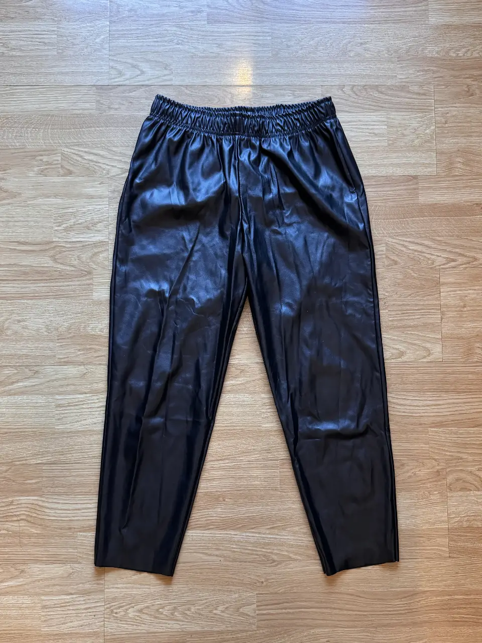 Pantalón de cuero sintético negro, tiro alto, con cintura elastizada. Ideal para un look moderno y versátil. Muy poco uso.