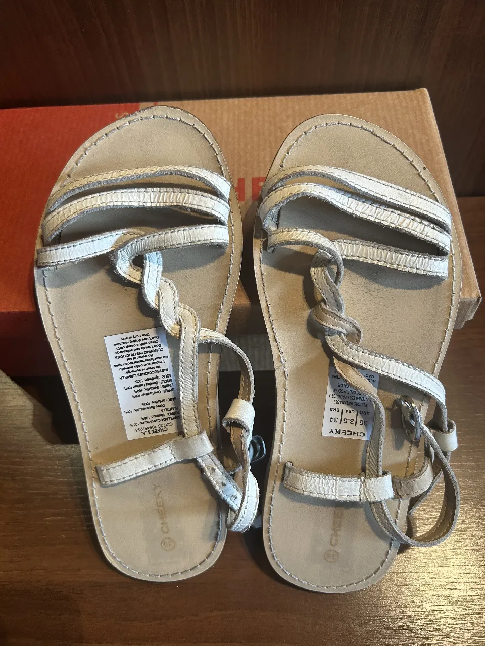 Sandalias blancas, con tiras finas entrelazadas y hebilla ajustable al tobillo. Ideales para un look casual de verano.