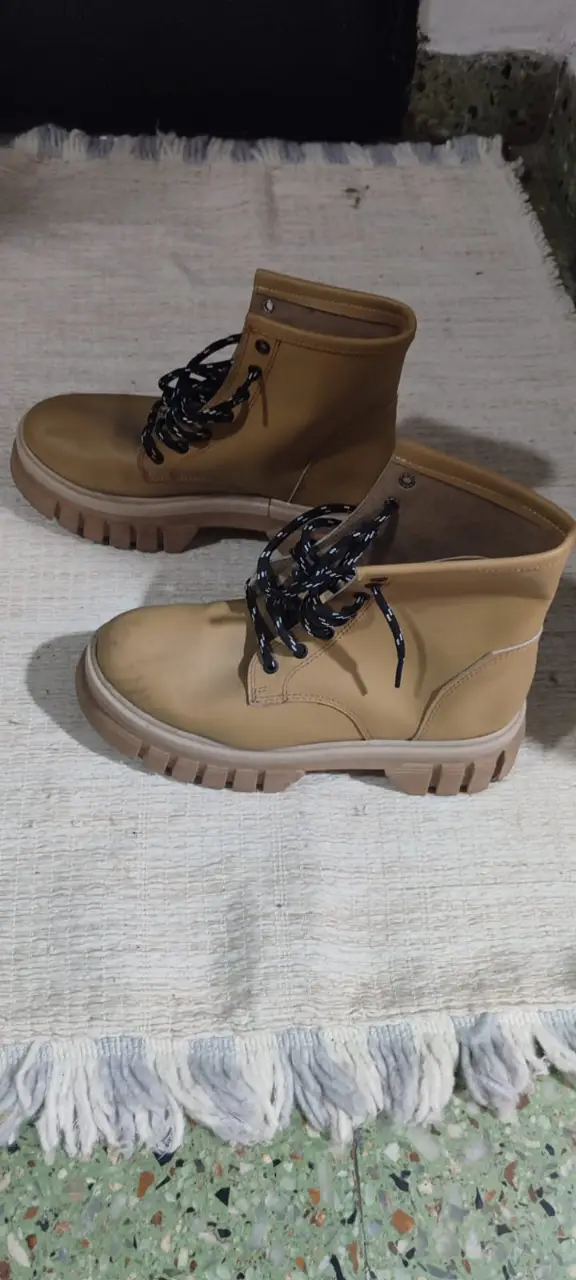 Borcegos de cuero sintético color marrón claro, con cordones negros y suela de goma. Ideales para un look casual y urbano.