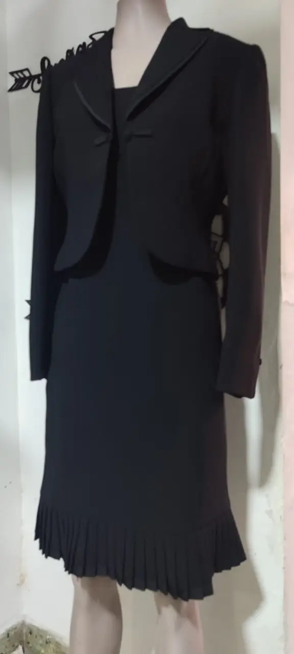 Elegante vestido midi negro con chaqueta a juego. El vestido presenta un diseño clásico con falda plisada y la chaqueta tiene un forro de estampado animal print. Ideal para eventos formales o de fiesta.