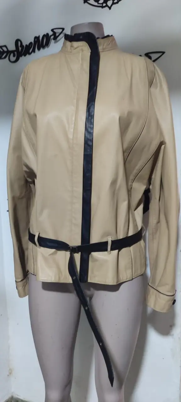 Chaqueta de cuero sintético color crema con detalles en negro. Diseño biker con cierre y cinturón. Ideal para un look casual y moderno.