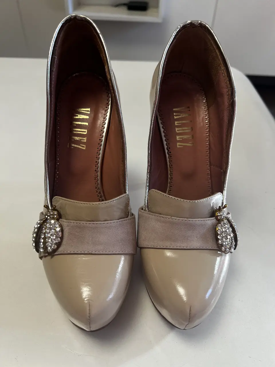 Elegantes zapatos de taco alto color crema con detalles plateados y apliques de strass. Ideales para eventos formales y fiestas.