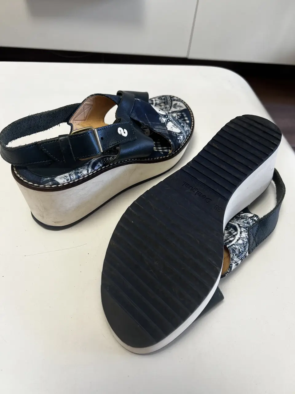 Sandalias de plataforma con diseño estampado en tonos azules y blancos. Tiras cruzadas y hebilla ajustable. Ideales para un look casual y cómodo.