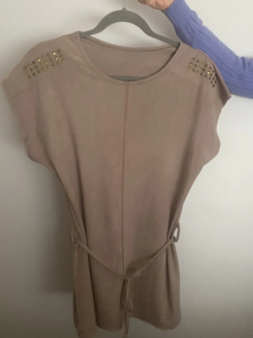 Remera manga corta gamuzada color visón con detalles de tachas doradas en los hombros. Incluye un cinturón fino del mismo color para ajustar a la cintura. Ideal para un look casual chic. Un solo uso.