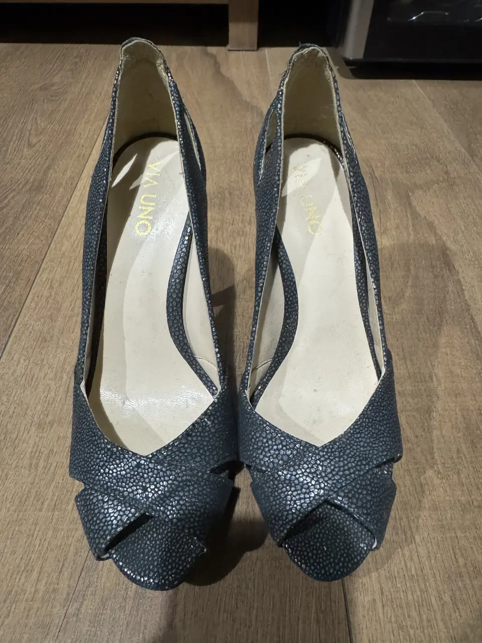 Elegantes zapatos de taco alto negros, con diseño cruzado en la parte delantera y detalles texturizados. Ideales para eventos formales o salidas nocturnas.