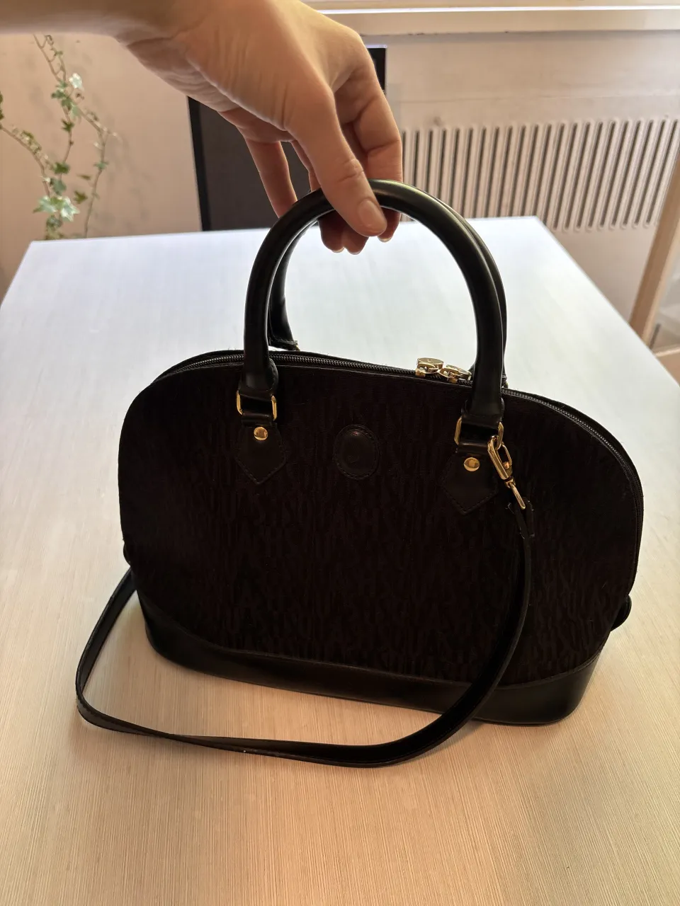 Bolso negro de cuero y tela con logo grabado. Tiene dos asas cortas y una correa larga desmontable. Cierre superior y bolsillo interior. Avios en dorado. vintage, excelente estado✨