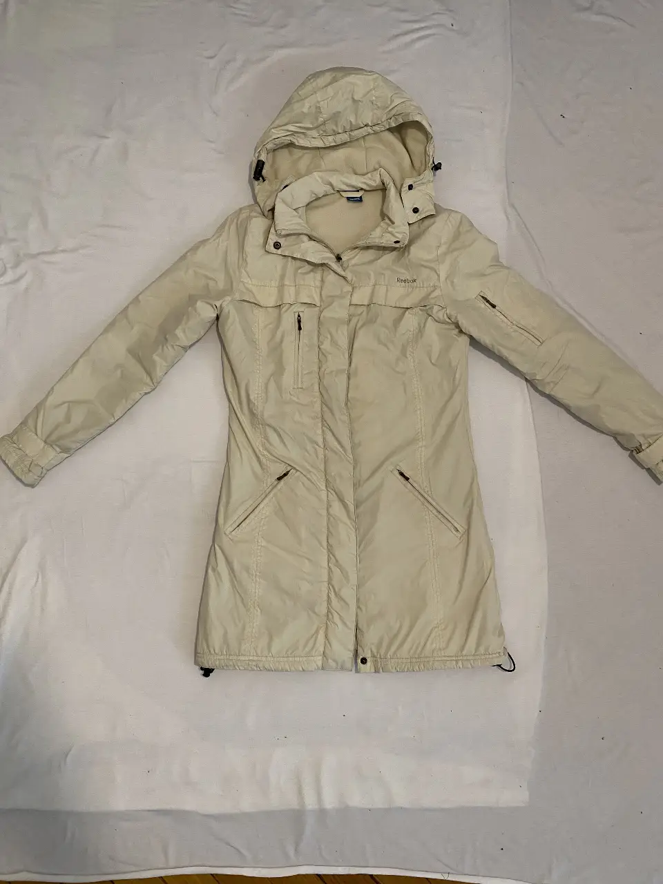 Campera Reebok larga de abrigo, color crudo, con capucha y bolsillos. Ideal para el invierno. Interior busto = 100 cmLargo = 90 cm   Cadera = 106 cm (ideal tamaño maximo de piernas t42 pantalon)