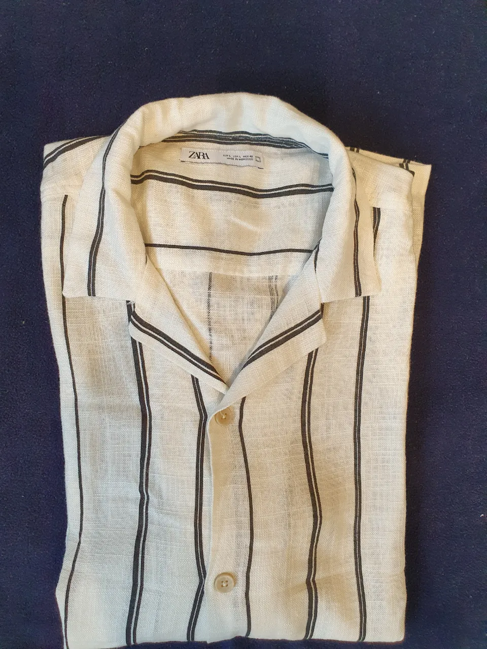 Camisa de hombre a rayas verticales en blanco y negro, de lino, con cuello y botones. Ideal para un look casual y fresco.