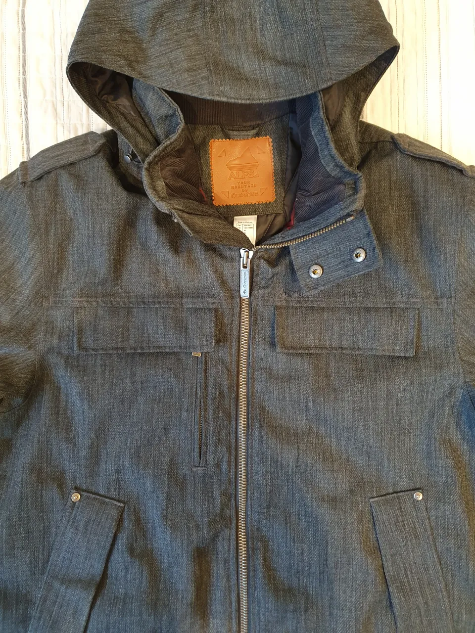 Campera de hombre Quechua gris con capucha desmontable. Impermeable. Posee cierre y bolsillos delanteros. Ideal para el invierno.
