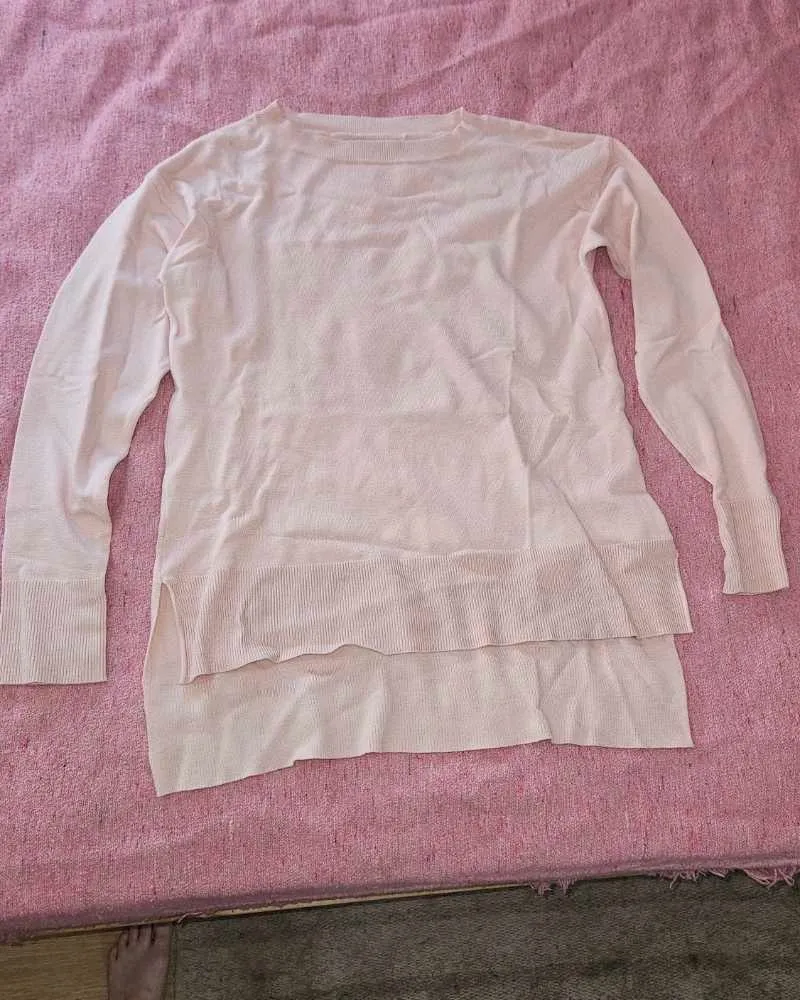 Sweater rosa palo de manga larga, con cuello redondo y tajos laterales. Diseño moderno y cómodo, ideal para el día a día.