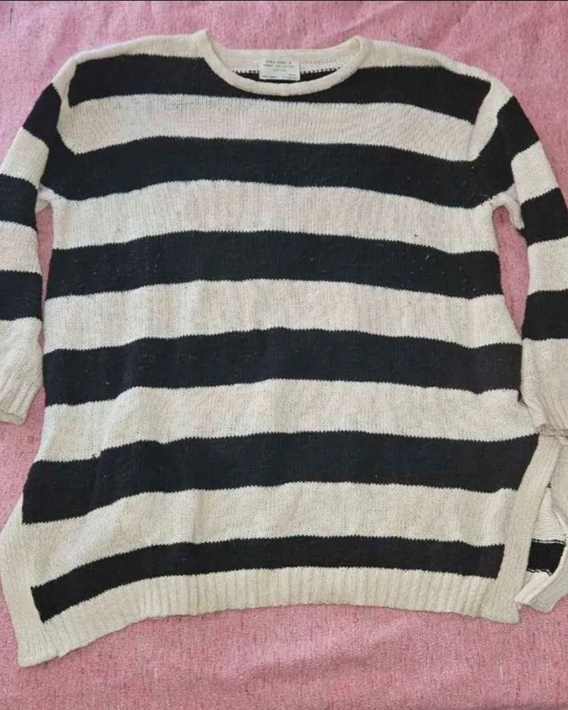 Sweater de hilo a rayas blancas y negras, ideal para un look casual y cómodo. Perfecto para los días frescos de entretiempo o para complementar un outfit de invierno.