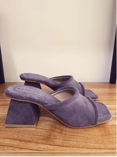 Sandalias de taco grueso color gris. Son súper cómodas y cancheras, ideales para elevar cualquier look. El diseño es abierto y con una tira ancha que cruza el empeine. El taco es cuadrado y de altura media, lo que las hace perfectas para usar todo el día.