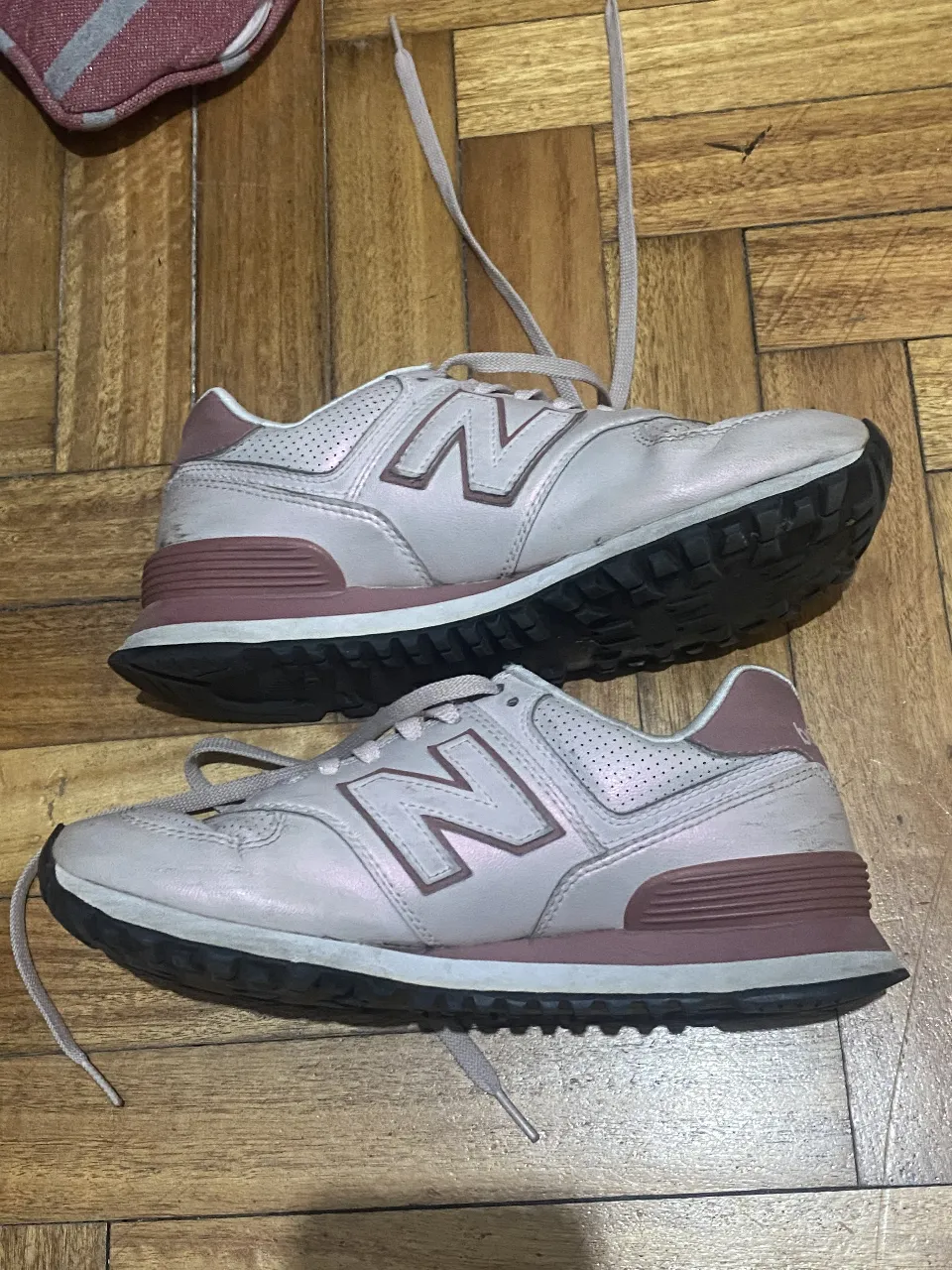 Zapatillas New Balance 574 en color rosa pálido con detalles en un tono más oscuro. Perfectas para un look casual y cómodo.