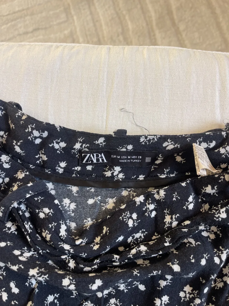 short pollera corta negra con estampa de flores blancas. Tiene volados y lazo para atar.