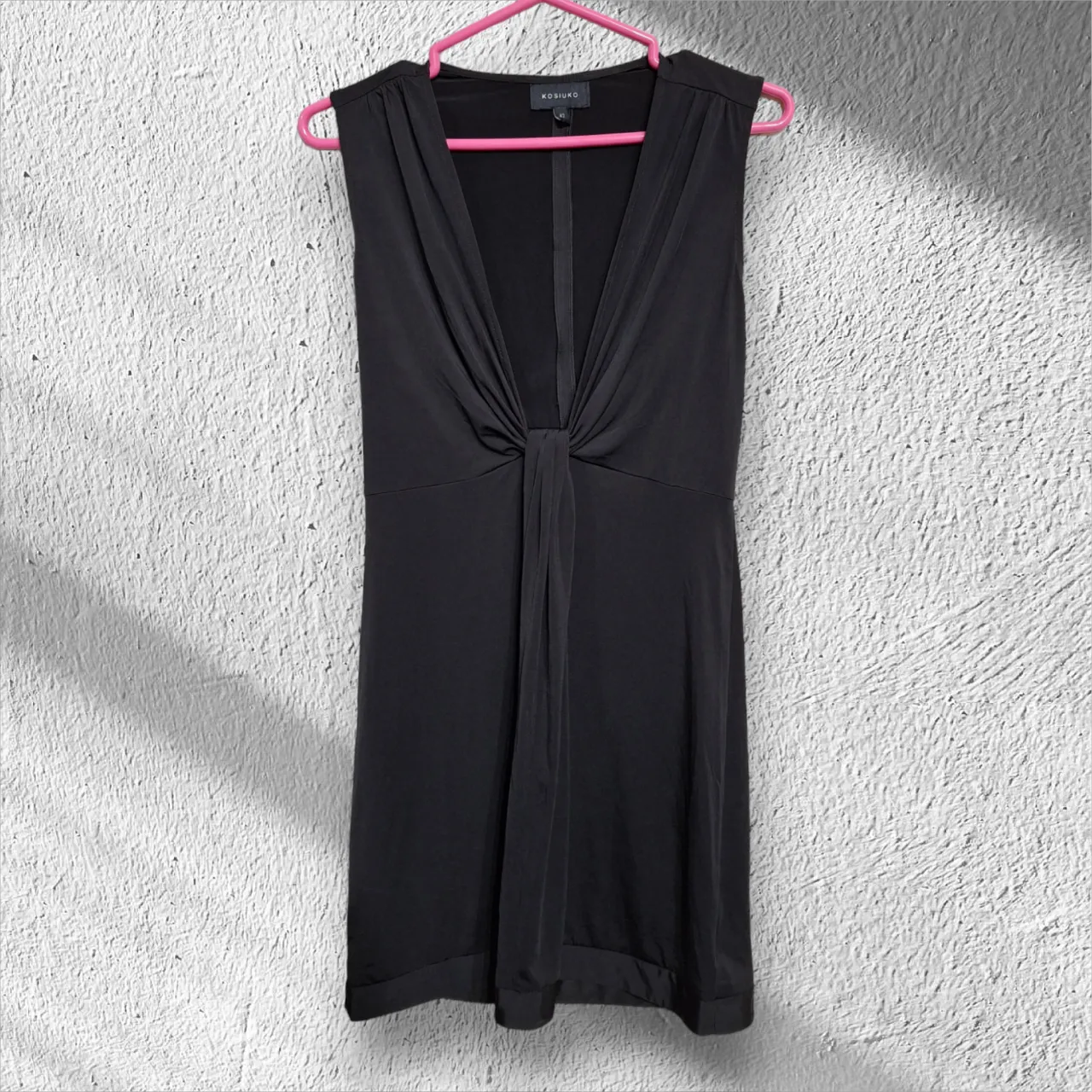 Vestido negro sin mangas con escote en V profundo y detalle de nudo en la cintura. Marca Kosiuko y talle 42.