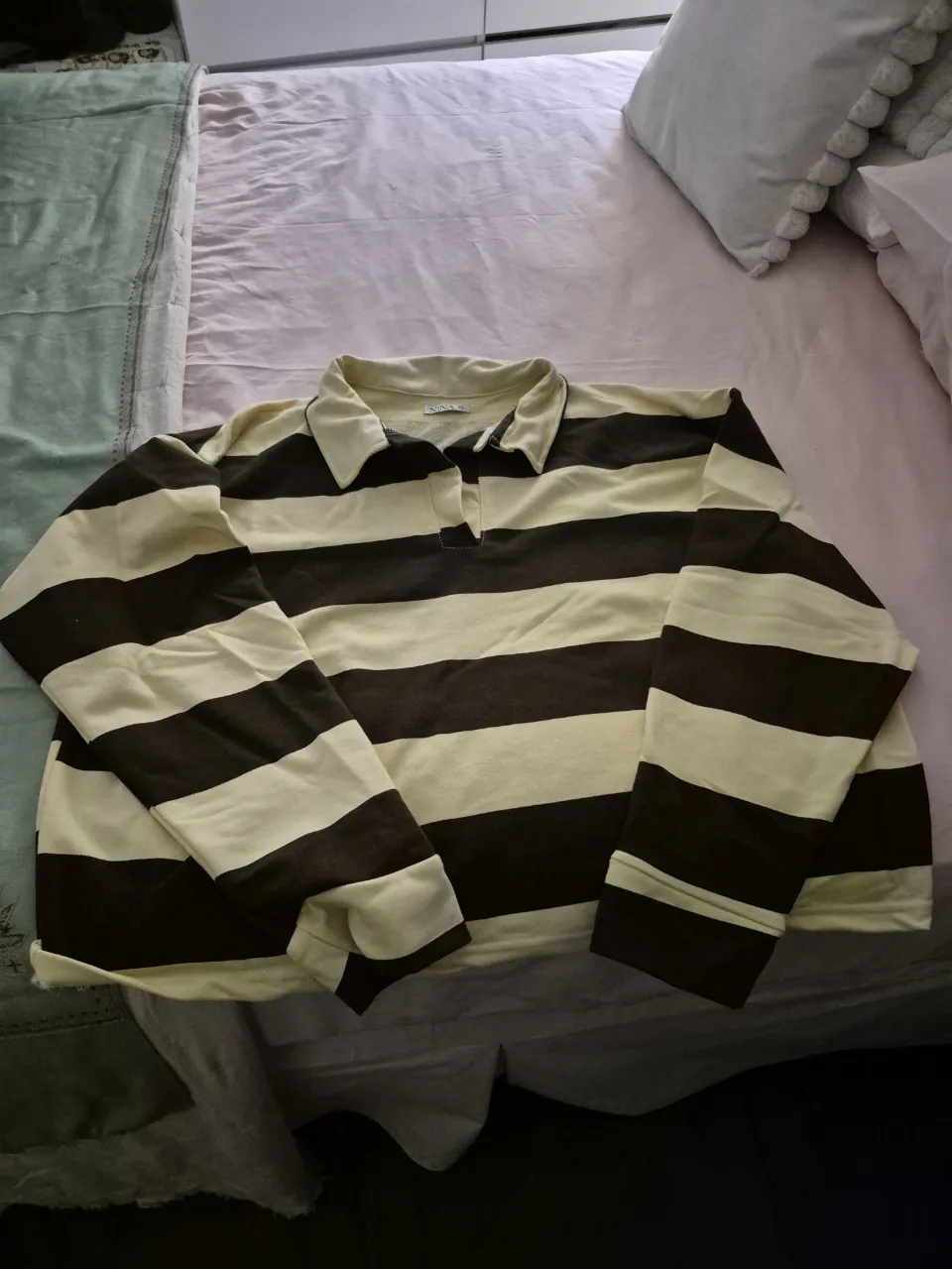 Remera de manga larga a rayas horizontales marrones y crudo, con cuello polo y botones.