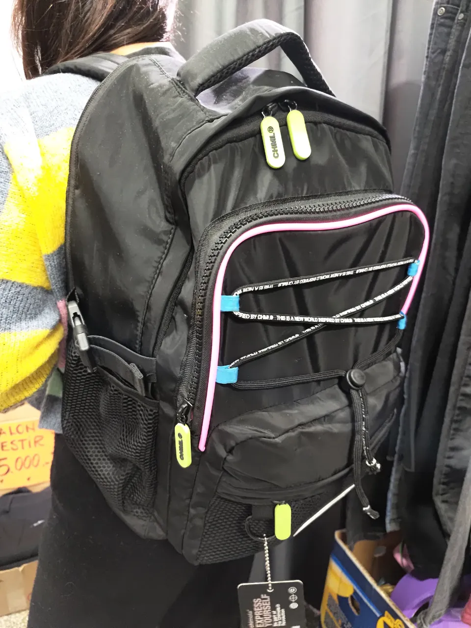 Mochila negra con detalles en rosa y azul, ideal para uso diario. Cuenta con múltiples compartimentos y un diseño moderno. Perfecta para llevar tus pertenencias con estilo.