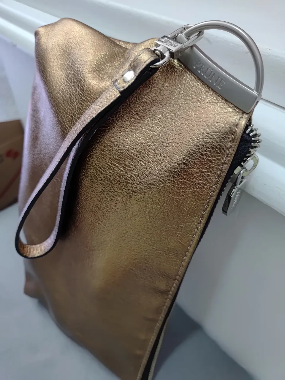 Cartera sobre dorada de la marca Prüne, con manija y cierre. Ideal para eventos y salidas. Cuero natural.