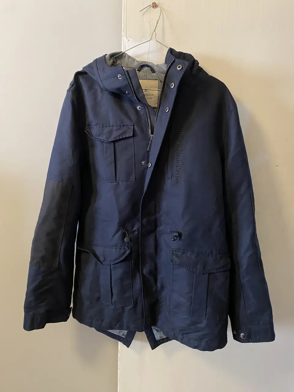 Campera de hombre azul marino con capucha y múltiples bolsillos. Diseño utilitario con detalles de la marca Herencia. Ideal para un look casual y urbano.