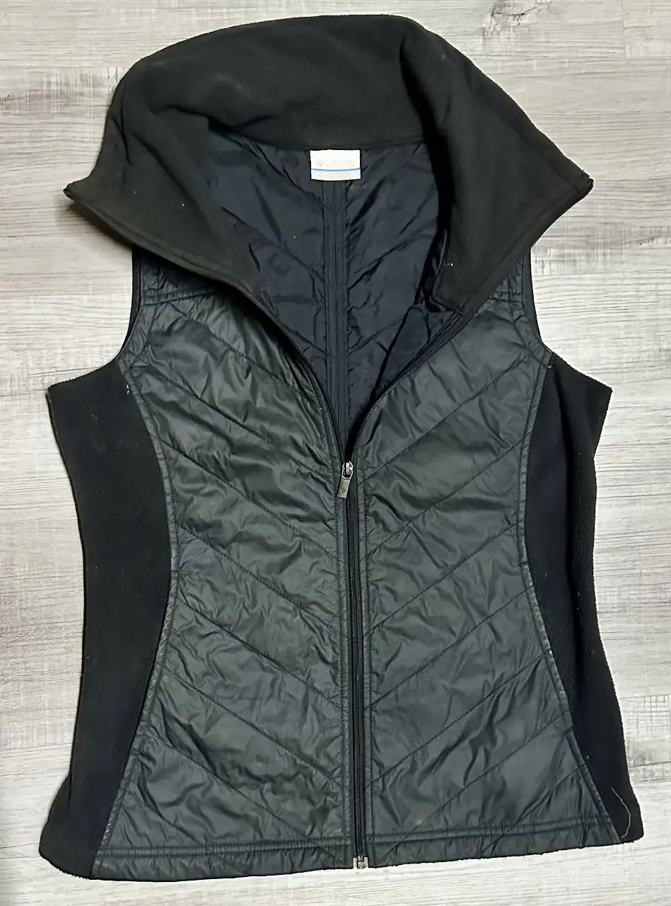 Chaleco Columbia negro para mujer, con diseño acolchado y detalles en polar. Ideal para el invierno, con cierre y cuello alto.