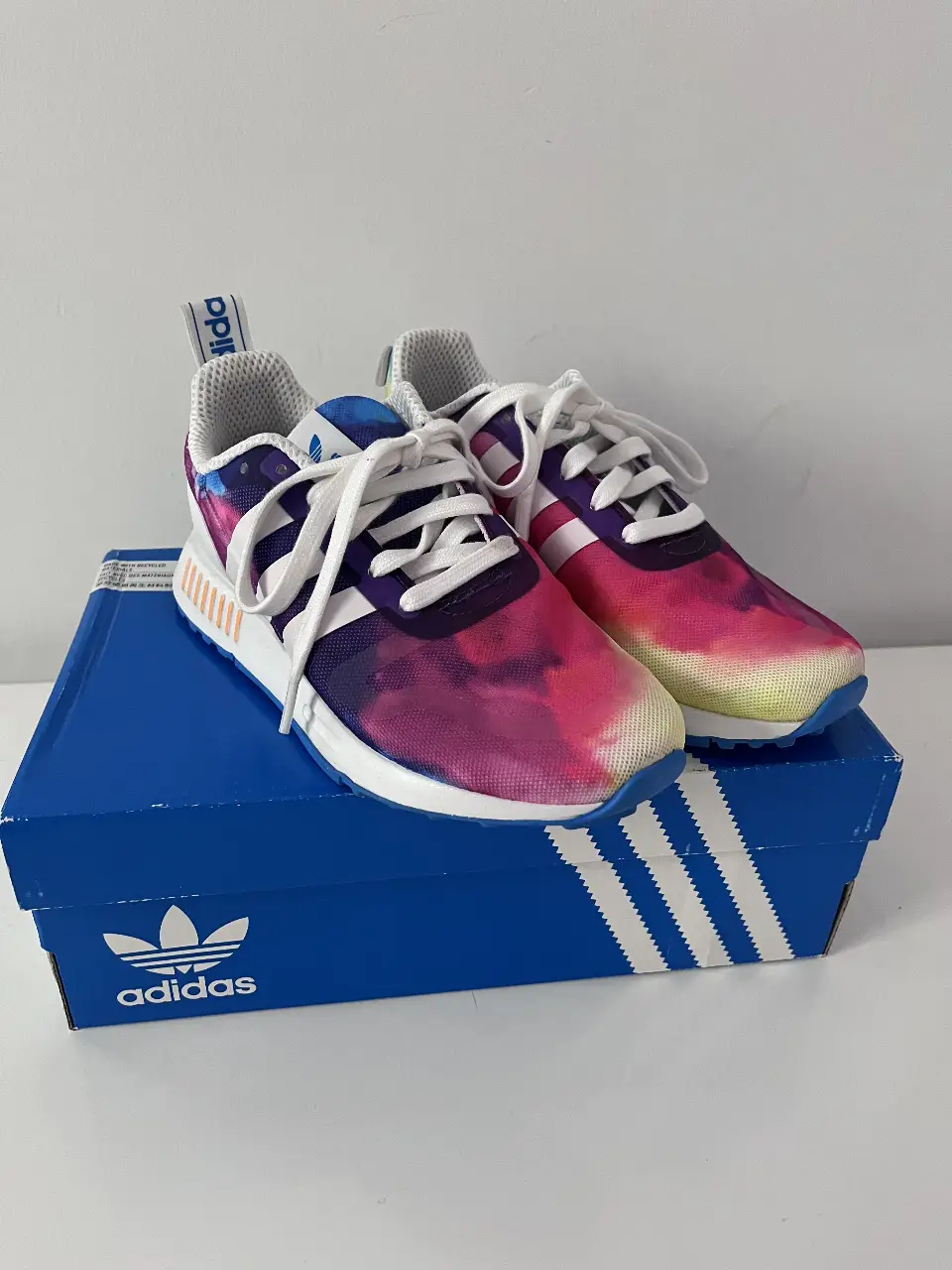 Zapatillas Adidas Multix W con diseño tie-dye en tonos violeta, rosa y amarillo. Ideales para un look deportivo y moderno.