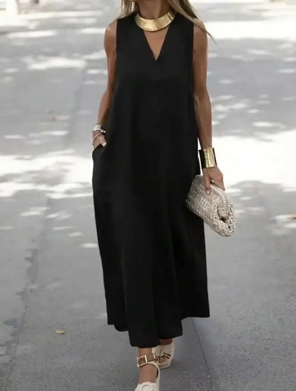 Vestido negro largo sin mangas, con escote en V y bolsillos laterales. Ideal para un look casual y cómodo.