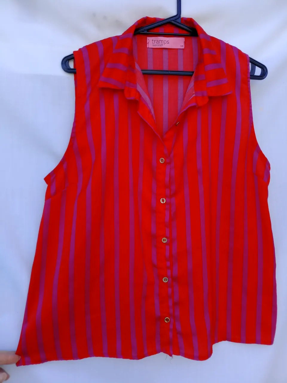 Remera sin mangas a rayas rojas y fucsia. Tiene cuello camisero y botones al frente. Ideal para un look casual y canchero.