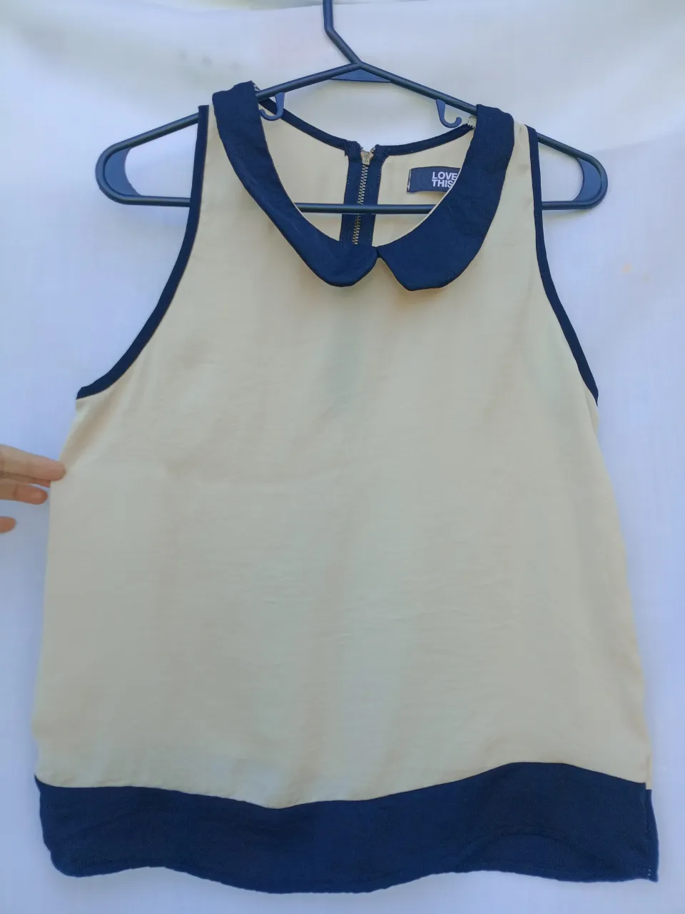 Top de seda color crema con cuello y mangas en negro. Diseño moderno y elegante, ideal para cualquier ocasión.