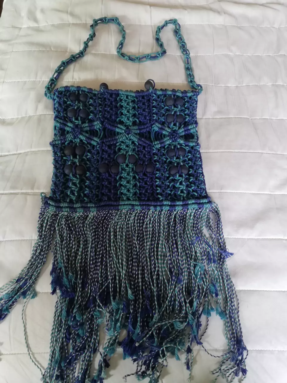 Cartera artesanal macramé con flecos, ideal para un look bohemio y casual. Diseño único con detalles en azul y verde.