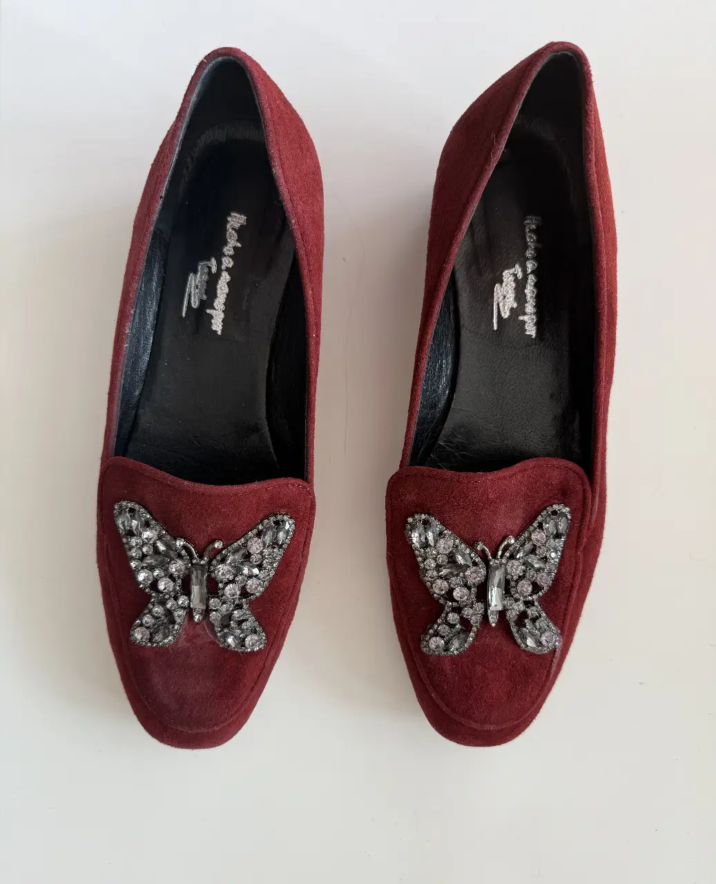 Mocasines de gamuza color borgoña con aplique de mariposa con strass. Ideales para un look elegante y sofisticado.