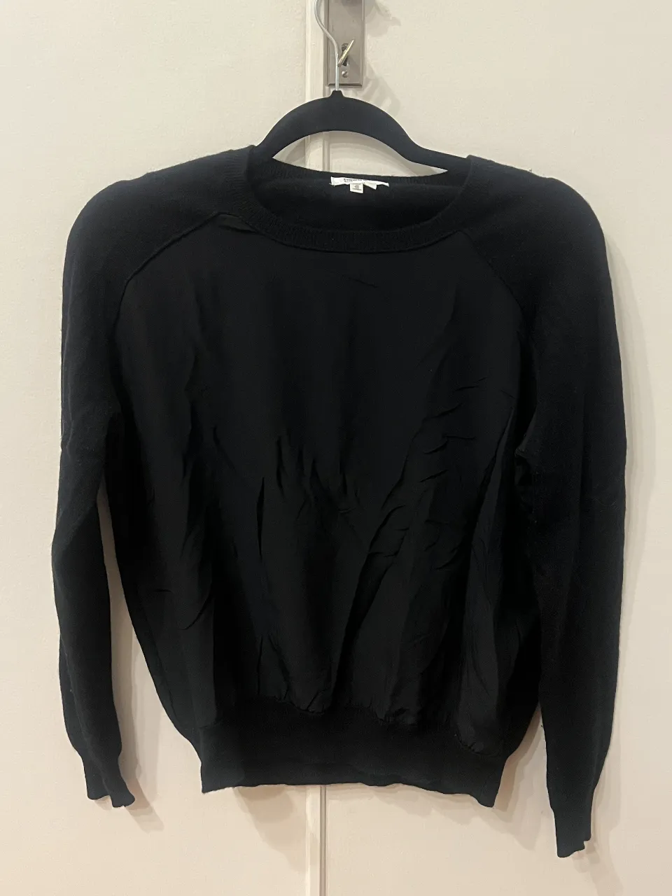Sweater negro de mujer, con mangas y espalda en tejido de punto y frente en tela lisa. Ideal para un look elegante y versátil.