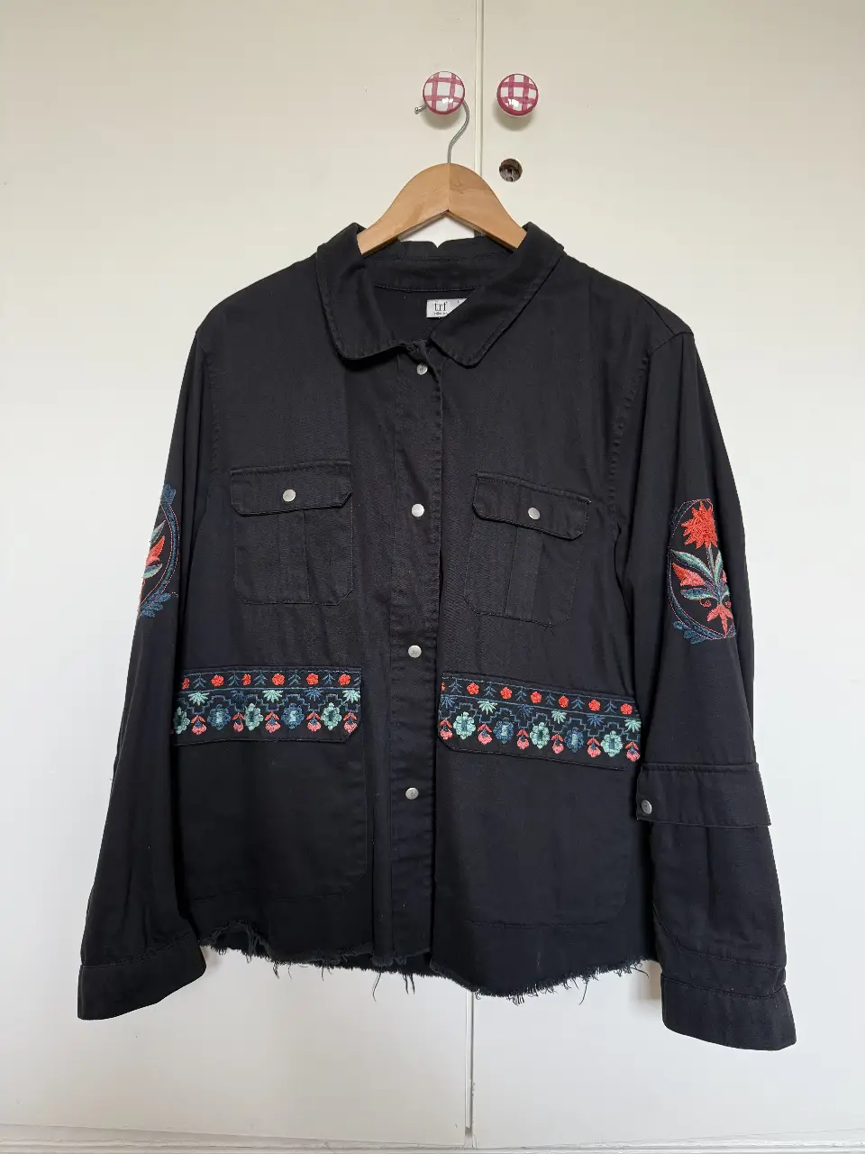 Campera de jean negra con bordados florales en mangas y bolsillos. Estilo boho y artesanal, ideal para un look casual y con onda.