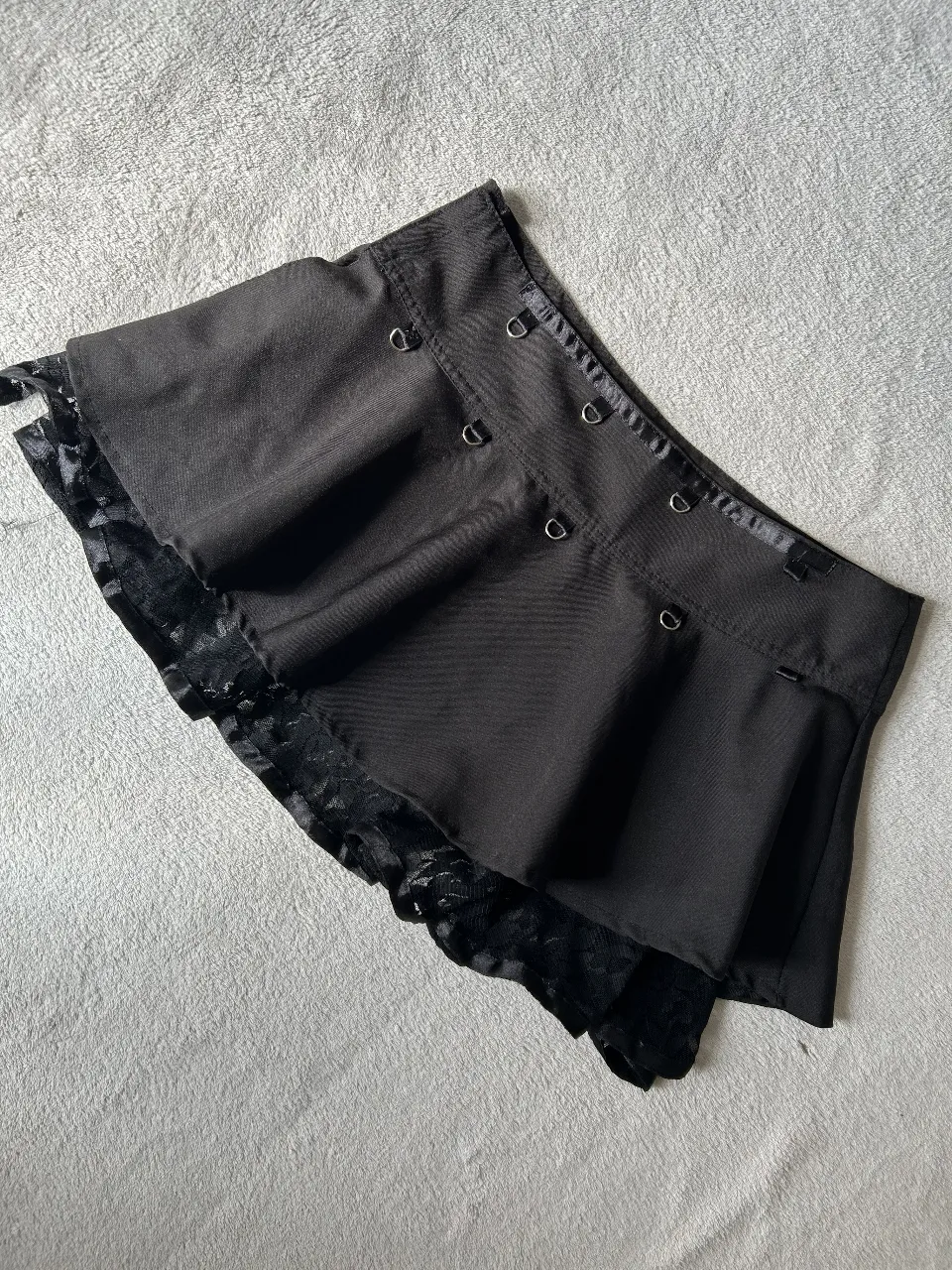 Pollera negra corta con detalles de encaje y argollas. Ideal para un look rocker o alternativo.