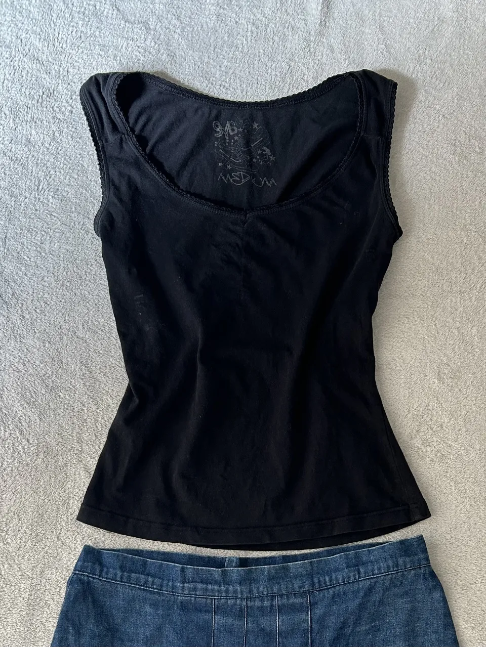 Musculosa negra con detalles de encaje en cuello y mangas. Ideal para un look casual o para usar como base de un outfit.