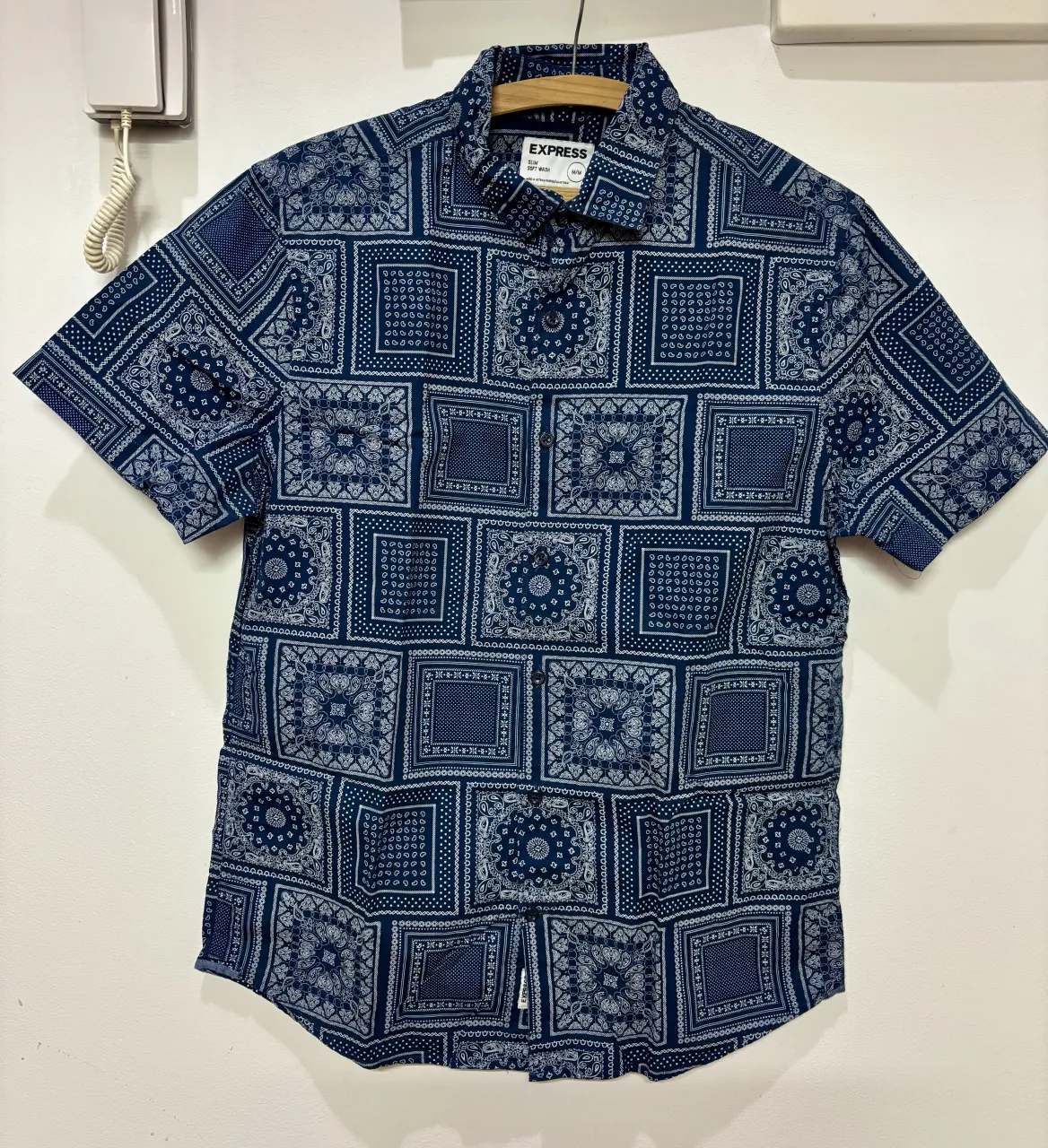 Camisa de manga corta con estampado de pañuelos en tonos azules y blancos. Posee cuello clásico y botones al frente.